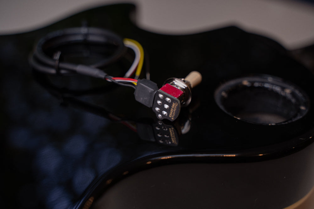 LesPaul style 3-way toggle switch resting on a guitar body.