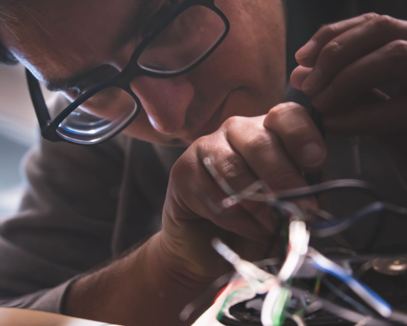 Person working with guitar wiring in a dimly lit setting